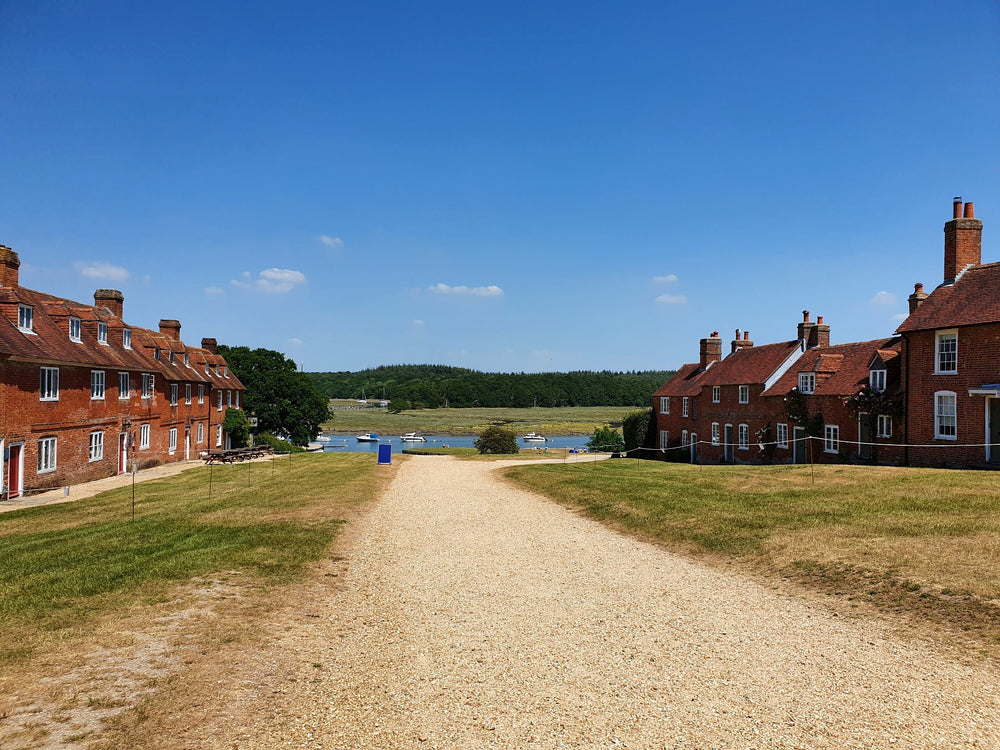 A broad village lane between red-brick cottages leading towards green countryside